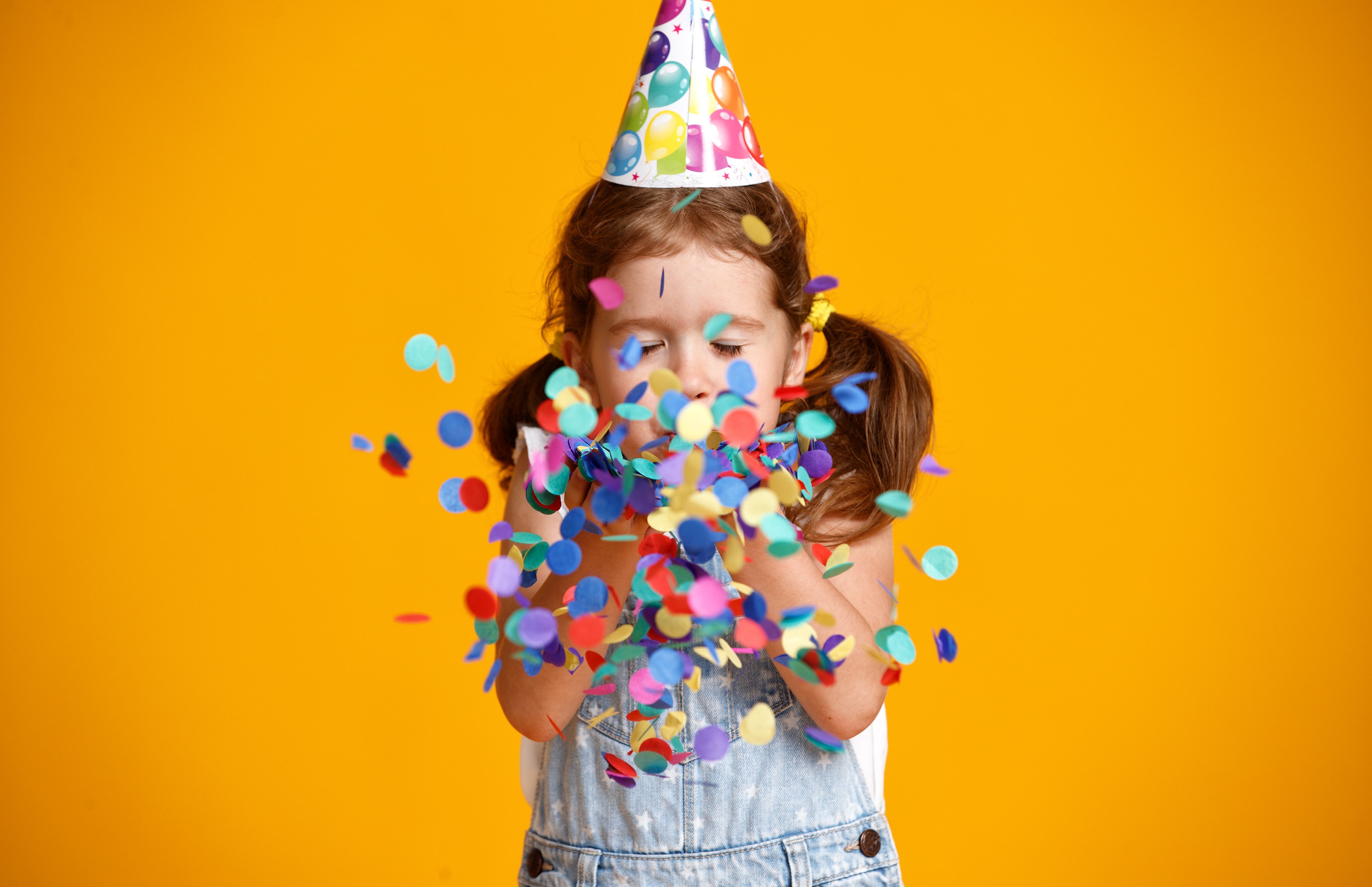 happy birthday child girl with confetti on yellow background